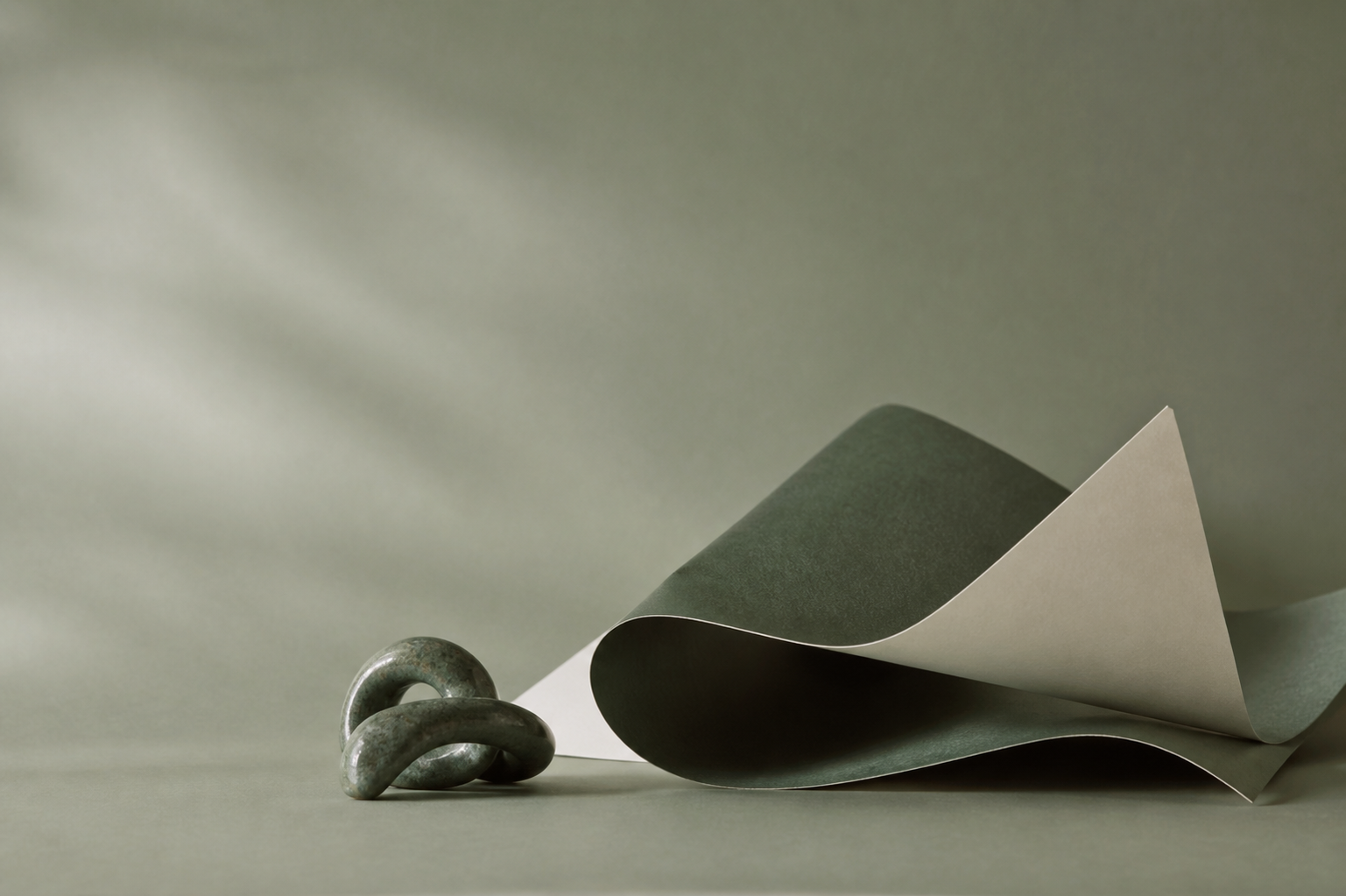 Forest-green folded paper sculpture and abstract ceramic form